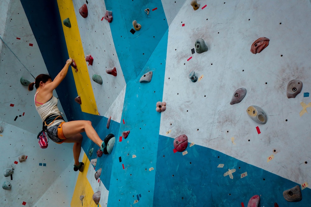 A climber is bouldering up a climbing gym wall