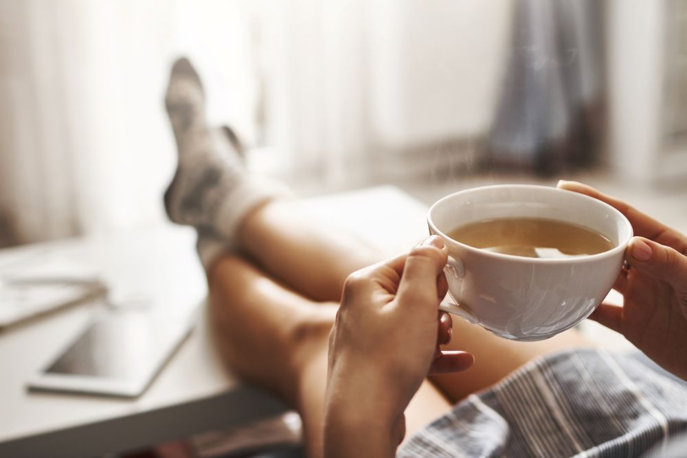 Person holding mug of tea with feet up